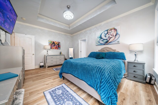 bedroom featuring light wood-type flooring, baseboards, ornamental molding, and a raised ceiling