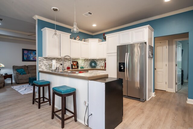 kitchen with stainless steel fridge, visible vents, white cabinets, a peninsula, and pendant lighting