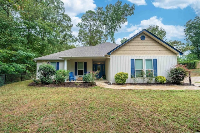 single story home with a shingled roof, fence, and a front lawn