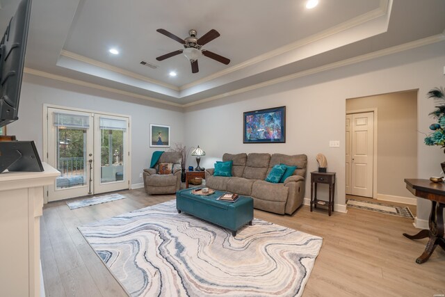 living area with visible vents, light wood-style floors, ornamental molding, french doors, and a raised ceiling