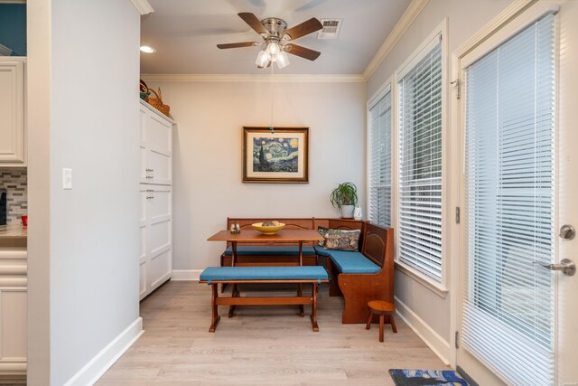 living area with baseboards, light wood-style floors, visible vents, and crown molding