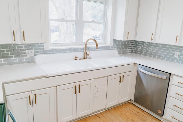 kitchen featuring white cabinetry, light wood-style floors, light countertops, stainless steel dishwasher, and decorative backsplash