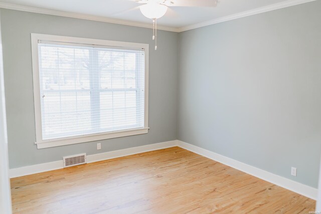 empty room with plenty of natural light, crown molding, visible vents, and wood finished floors