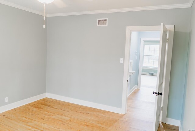 spare room featuring ornamental molding, visible vents, and wood finished floors