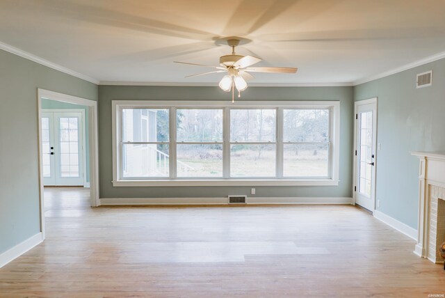 interior space featuring ornamental molding, a fireplace, light wood-style flooring, and visible vents