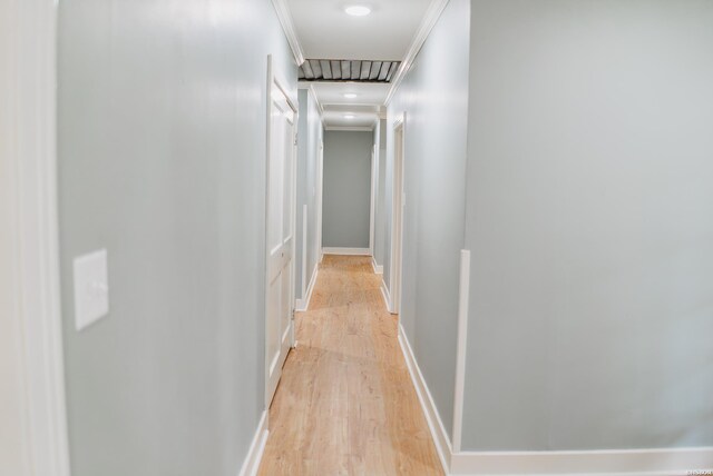 hallway with ornamental molding, light wood-type flooring, and baseboards