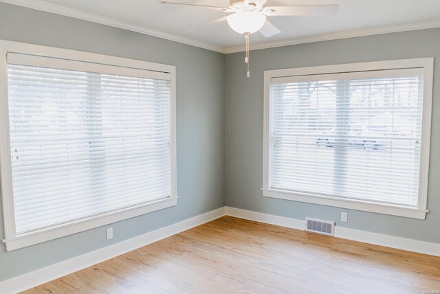 unfurnished room with light wood finished floors, baseboards, visible vents, and crown molding