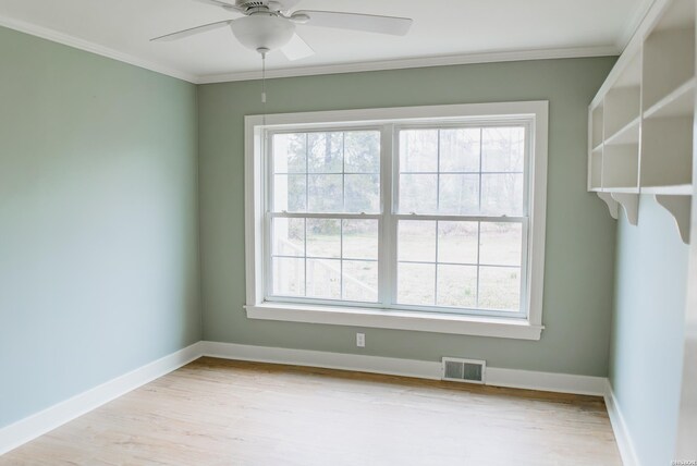 spare room featuring light wood-type flooring, a wealth of natural light, visible vents, and crown molding