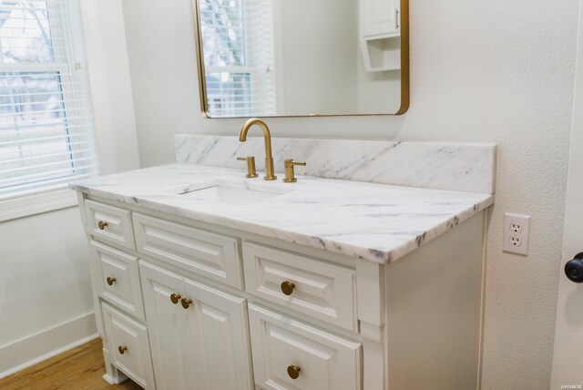 bathroom featuring a wealth of natural light, vanity, baseboards, and wood finished floors