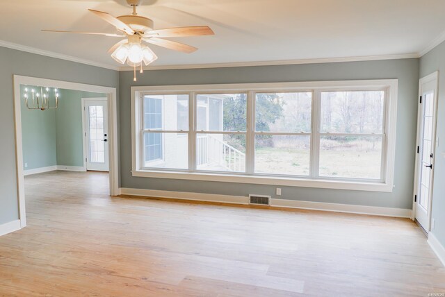 empty room featuring light wood-style flooring, ceiling fan with notable chandelier, visible vents, baseboards, and crown molding