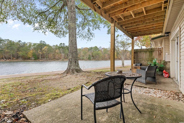 view of patio featuring a water view and fence