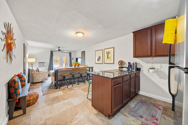 kitchen with baseboards, a breakfast bar, open floor plan, freestanding refrigerator, and a peninsula