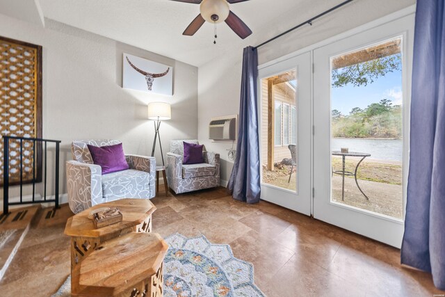 sitting room featuring ceiling fan, a wall mounted AC, and a water view