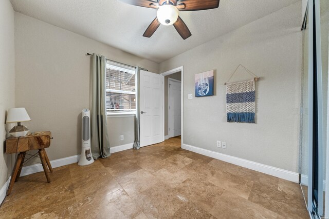 unfurnished bedroom with ceiling fan, a textured ceiling, and baseboards