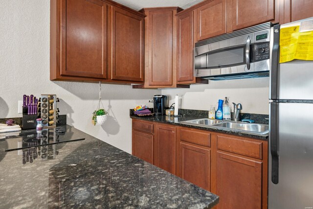 kitchen with appliances with stainless steel finishes, brown cabinetry, and a sink