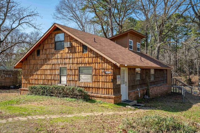 view of front of house with a shingled roof, a front lawn, a detached garage, and fence