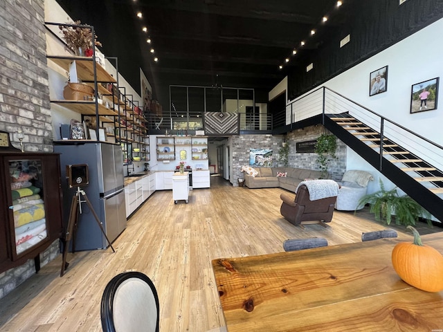 interior space with light wood-style floors, a towering ceiling, and stairs