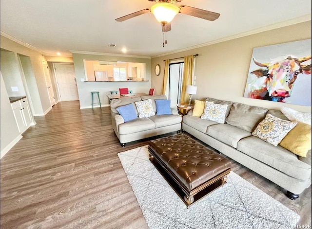 living room featuring visible vents, baseboards, ceiling fan, ornamental molding, and wood finished floors