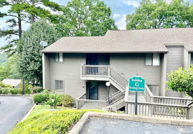 view of front of property featuring a shingled roof, stairs, and uncovered parking