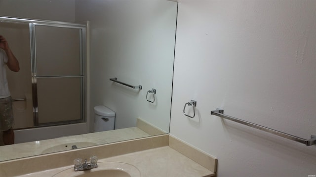 bathroom featuring toilet, an enclosed shower, and vanity