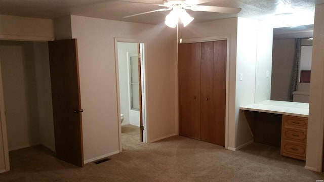 unfurnished bedroom with ceiling fan, connected bathroom, light colored carpet, visible vents, and a closet