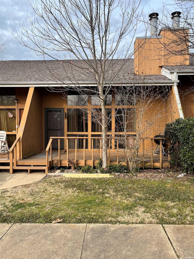 back of property featuring a shingled roof, a lawn, and a wooden deck