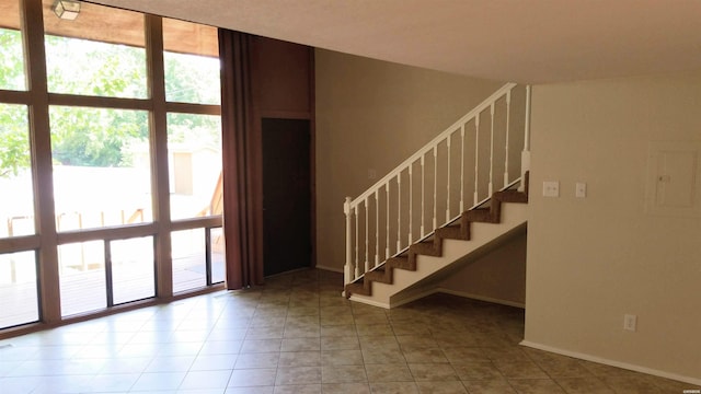 interior space featuring stairs, expansive windows, baseboards, and tile patterned floors