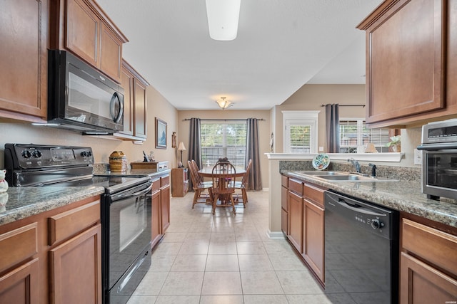 kitchen featuring brown cabinetry, a sink, black appliances, and light tile patterned floors