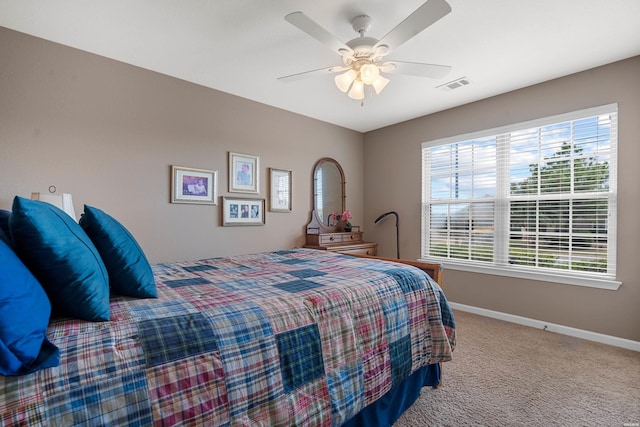 carpeted bedroom featuring a ceiling fan, multiple windows, visible vents, and baseboards