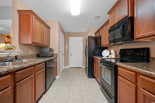 kitchen featuring brown cabinets, dark countertops, visible vents, a sink, and black appliances