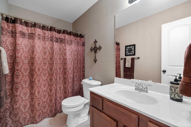 bathroom with a textured wall, vanity, and toilet