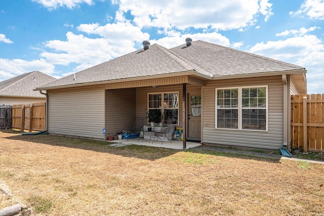 back of house featuring roof with shingles, fence, a lawn, and a patio