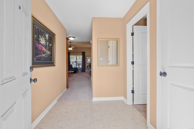 corridor featuring light colored carpet and baseboards