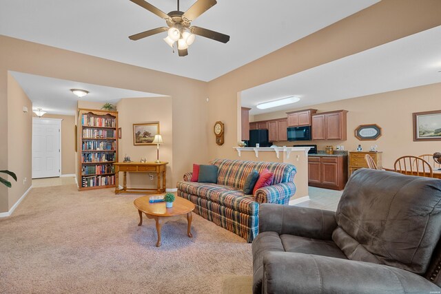 living area featuring baseboards, ceiling fan, and light colored carpet