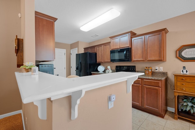 kitchen featuring black appliances, a peninsula, light countertops, and visible vents