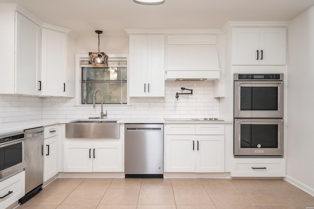 kitchen with stainless steel appliances, light countertops, a sink, and white cabinetry