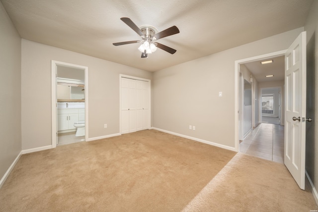 unfurnished bedroom with connected bathroom, light colored carpet, a ceiling fan, baseboards, and a closet