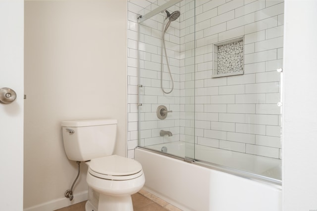 bathroom featuring toilet, baseboards, bath / shower combo with glass door, and tile patterned flooring