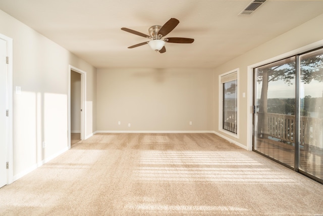 empty room with light colored carpet, visible vents, ceiling fan, and baseboards