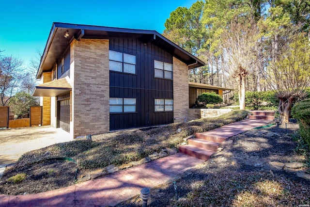 view of side of home with concrete driveway, brick siding, and an attached garage