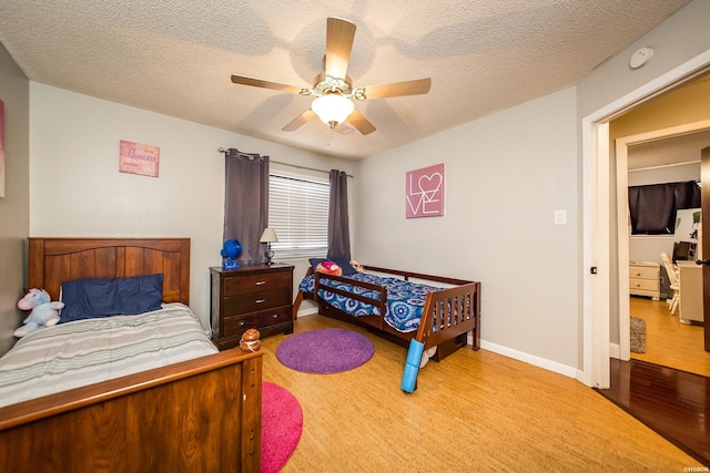 bedroom featuring ceiling fan, a textured ceiling, wood finished floors, and baseboards