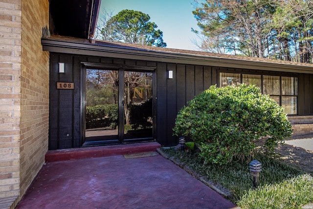 property entrance with board and batten siding and brick siding