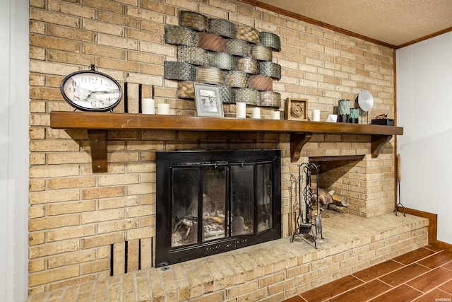 details featuring a textured ceiling, a brick fireplace, wood finished floors, and crown molding