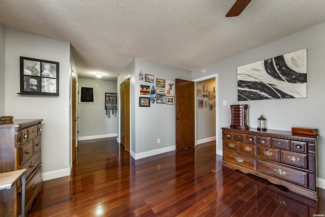 hall with dark wood-type flooring, a textured ceiling, and baseboards