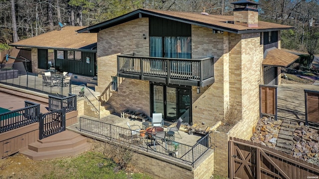 rear view of property with a chimney, fence, outdoor dining area, a patio area, and brick siding