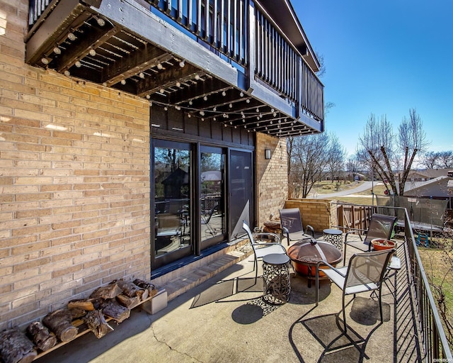 view of patio / terrace with an outdoor fire pit and a balcony