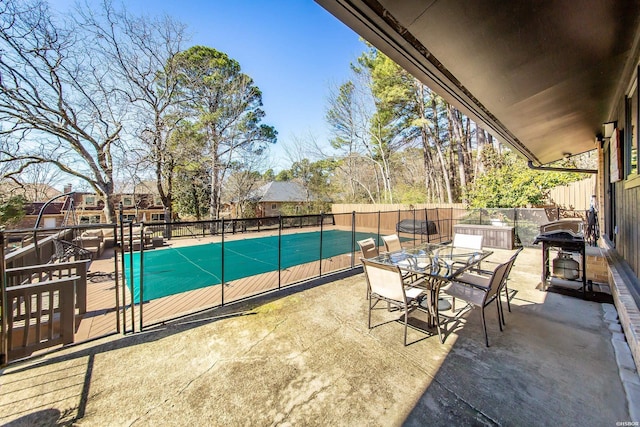 view of patio featuring outdoor dining space, fence, and a fenced in pool