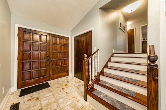 entryway featuring stairway, baseboards, visible vents, and vaulted ceiling