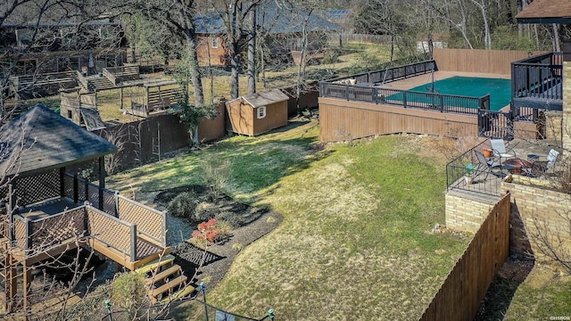 view of yard with an outbuilding, a storage unit, a fenced backyard, and a fenced in pool