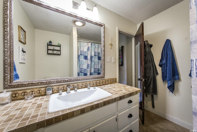 bathroom featuring backsplash, a textured ceiling, vanity, tile patterned flooring, and baseboards